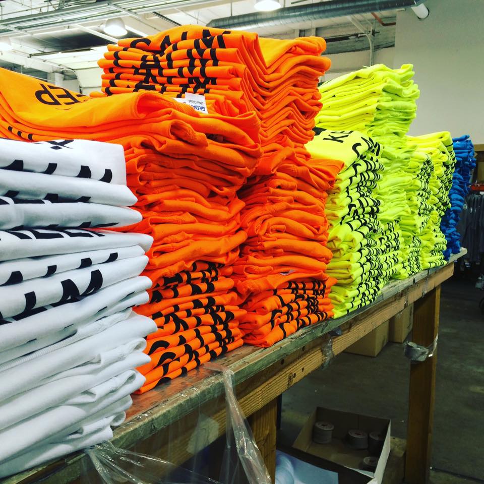 stacks of white, orange, blue and green t-shirts